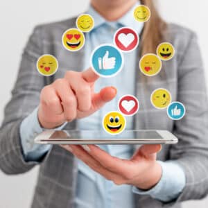 Social media emoticons superimposed on a business womans phone.